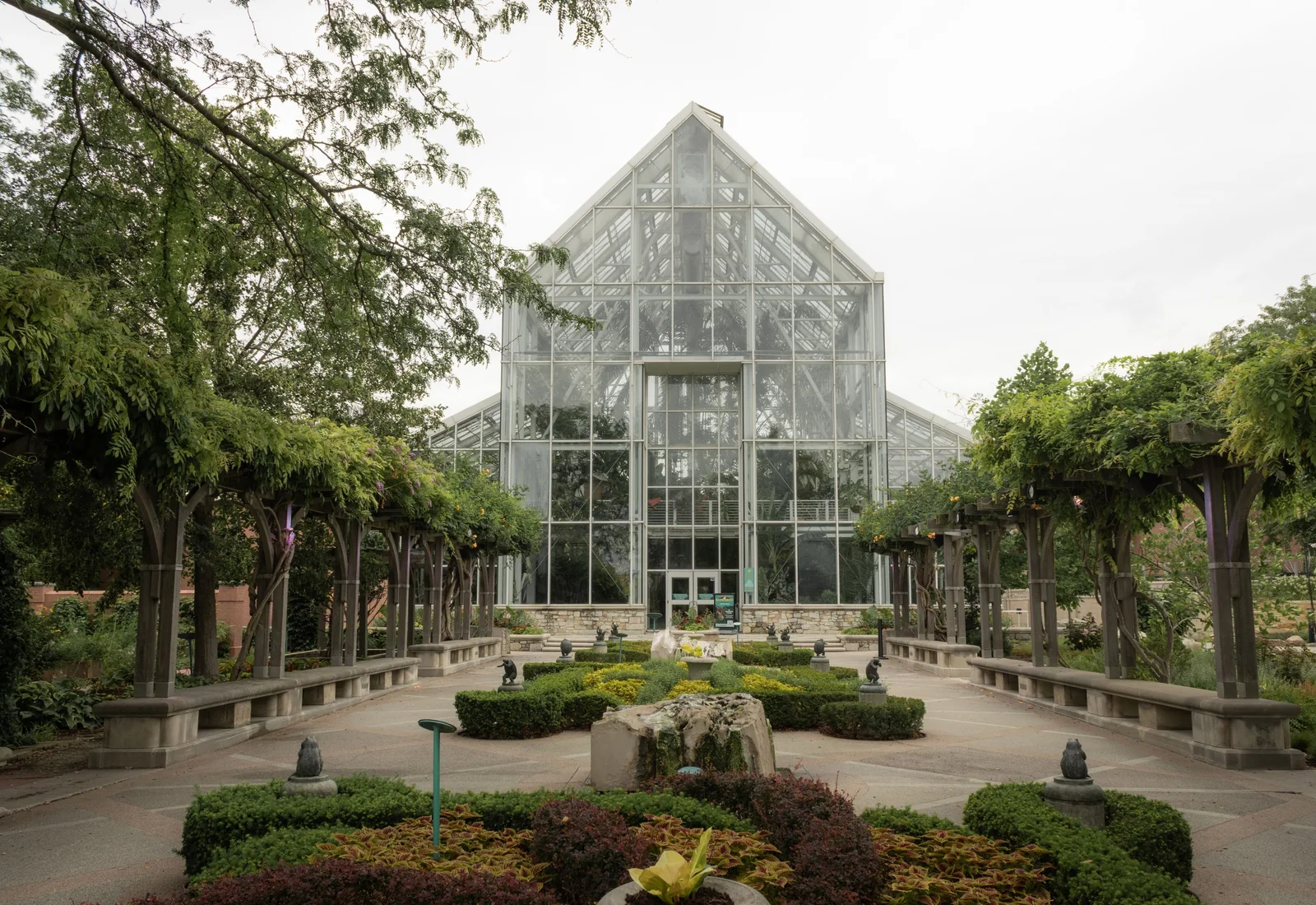 A glass conservatory surrounded by lush botanical plantings.